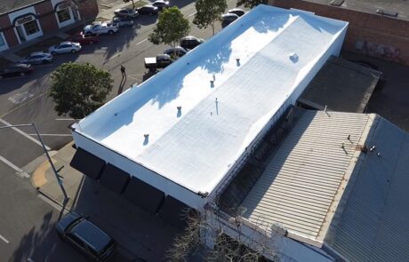 Aerial view of a commercial building with a newly installed white flat roof by Creative Roofs.