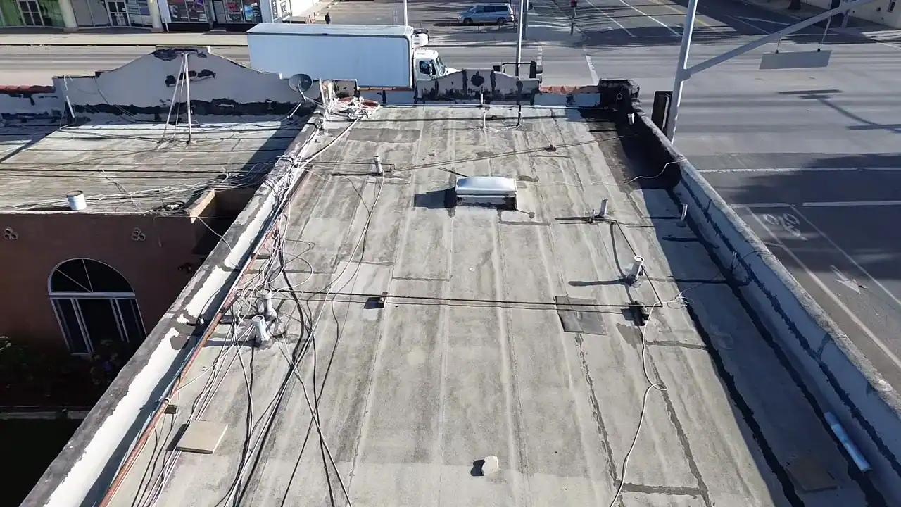 Roofers inspect a flat roof with visible vents and wiring, showcasing craftsmanship and roofing materials.